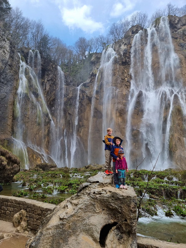 Two kids stand in front of a large waterfall in Croatia, one of the best places to visit Europe with outdoor kids.