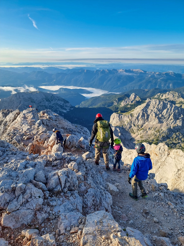 A mom and her kids hike along a rocky, mountain path in Slovenia.