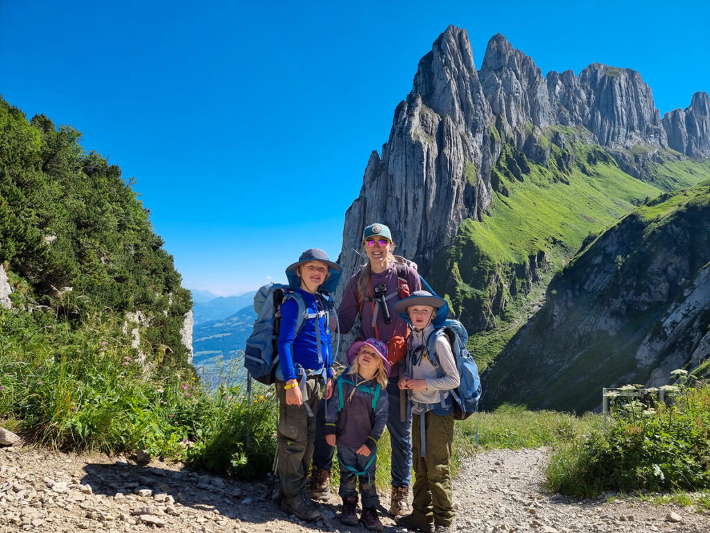 A family of four poses together with their hiking gear, while trekking in Switzerland.