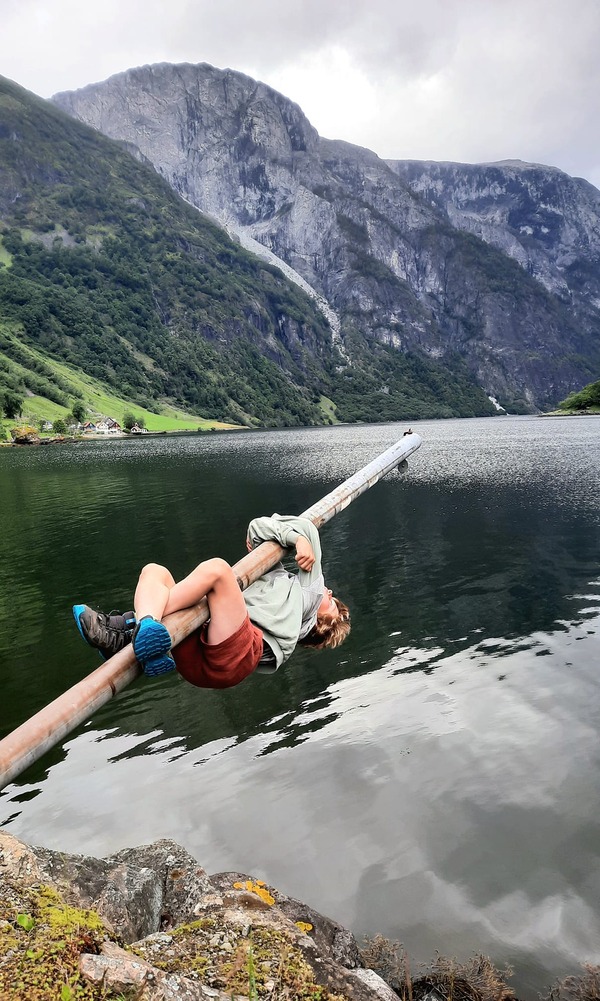 A young boy hangs over the water of a lake in Norway.