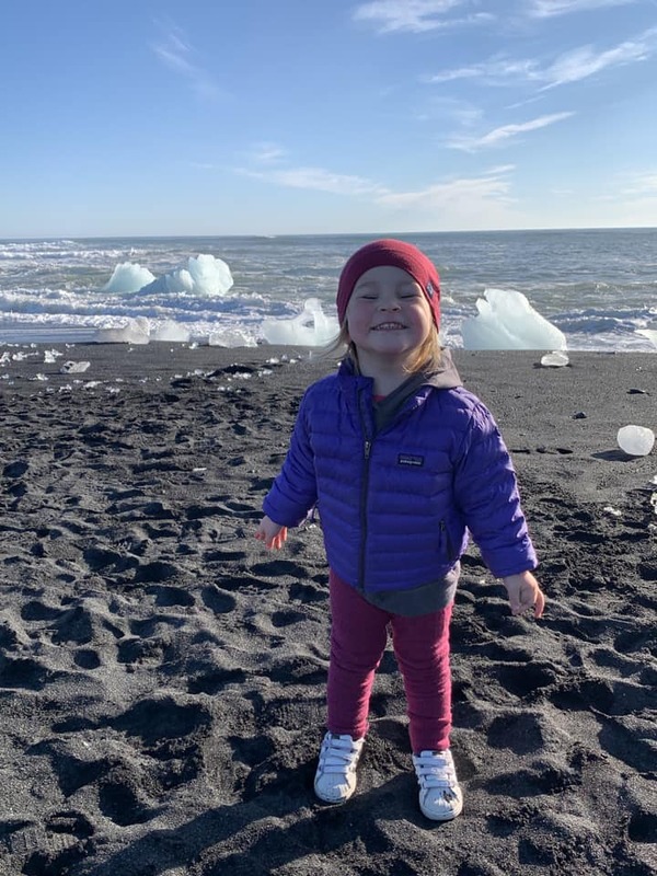 A young girl smiles as she explores Diamond Beach in Iceland, one of the best places to visit in Europe with kids.