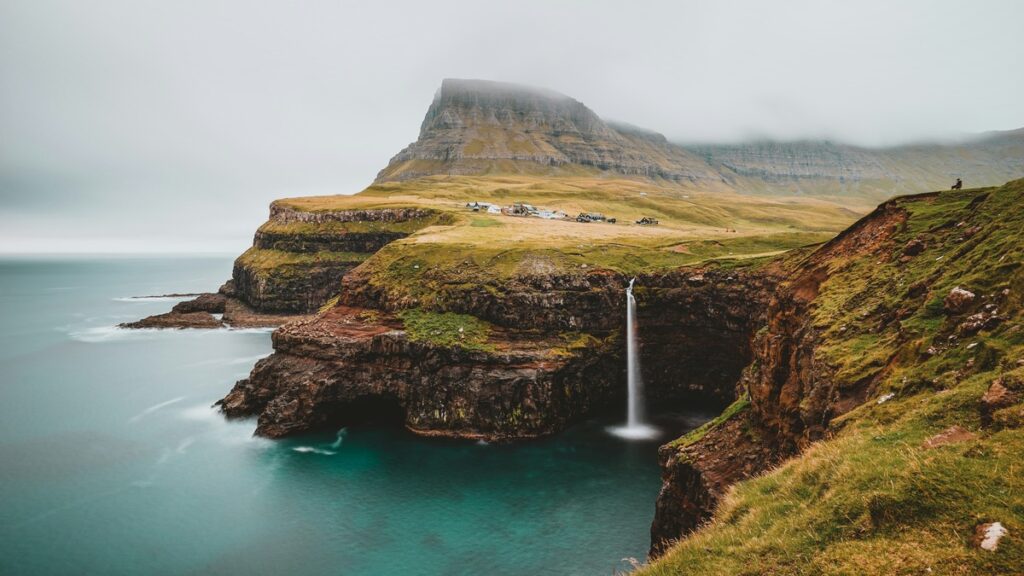 A waterfall cascades into the ocean off the coast of the Faroe Islands.