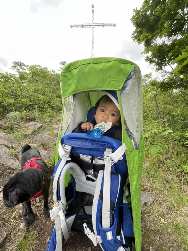 A young baby rests in a carrier while hiking in the rain.