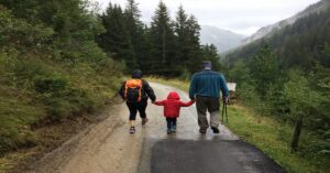 A family of three hikes together in the rain.